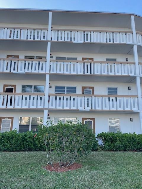 A three-story apartment building exterior features white walls, brown railings, and a central green bush — 2075 Cornwall D # 2075, Boca Raton FL 33434, BOCA RATON, FL