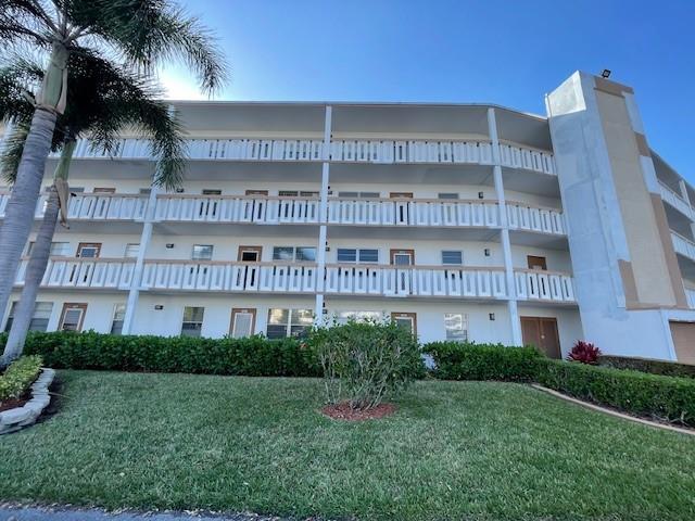 A multi-story apartment building features white exterior walls, open balconies, and a palm tree — 2075 Cornwall D # 2075, Boca Raton FL 33434, BOCA RATON, FL