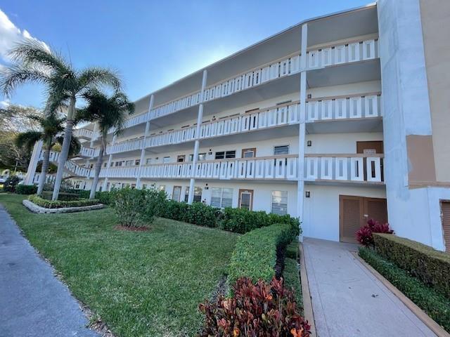 A three-story apartment building features white balconies and a landscaped lawn with palm trees — 2075 Cornwall D # 2075, Boca Raton FL 33434, BOCA RATON, FL