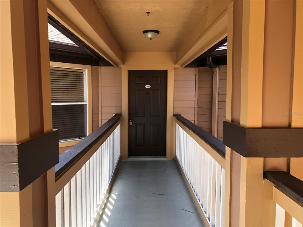 A covered outdoor walkway leads to a dark brown front door marked with number 308 — 482 N PIN OAK PLACE UNIT 308, LONGWOOD, FL