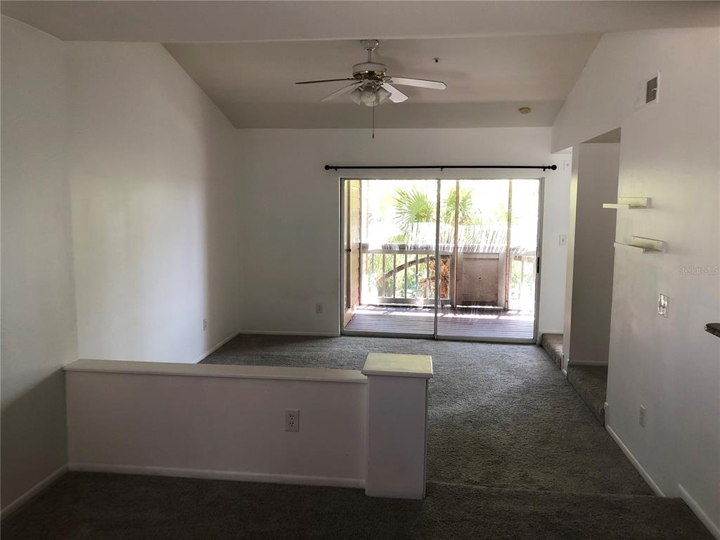 An empty living room with gray carpet, a ceiling fan, and a sliding glass door — 482 N PIN OAK PLACE UNIT 308, LONGWOOD, FL