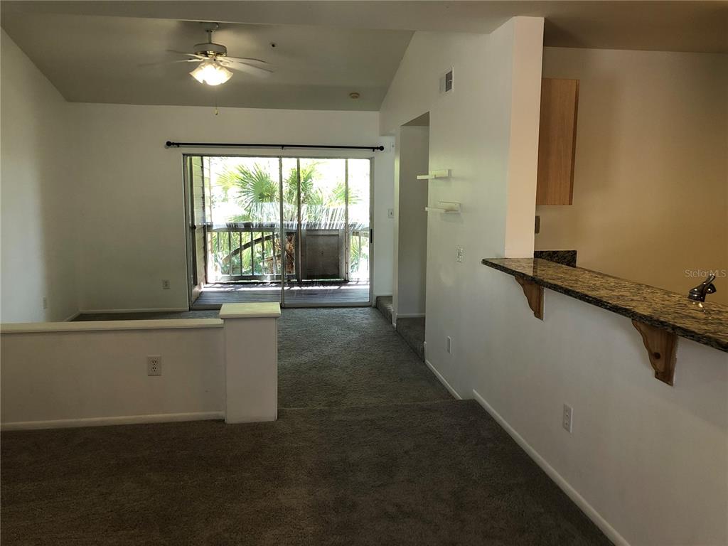 A living room with gray carpet, a ceiling fan, and a sliding door to a balcony — 482 N PIN OAK PLACE UNIT 308, LONGWOOD, FL