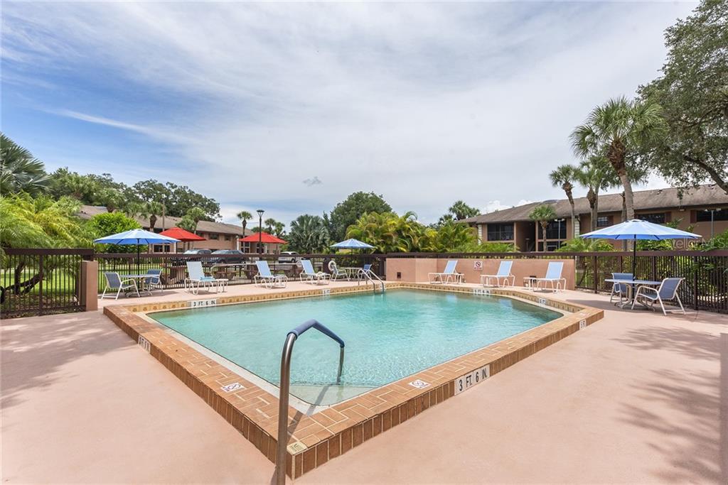 A rectangular outdoor swimming pool with a brick border and surrounding lounge chairs and umbrellas — 1515 FORREST NELSON BOULEVARD UNIT C202, PORT CHARLOTTE, FL