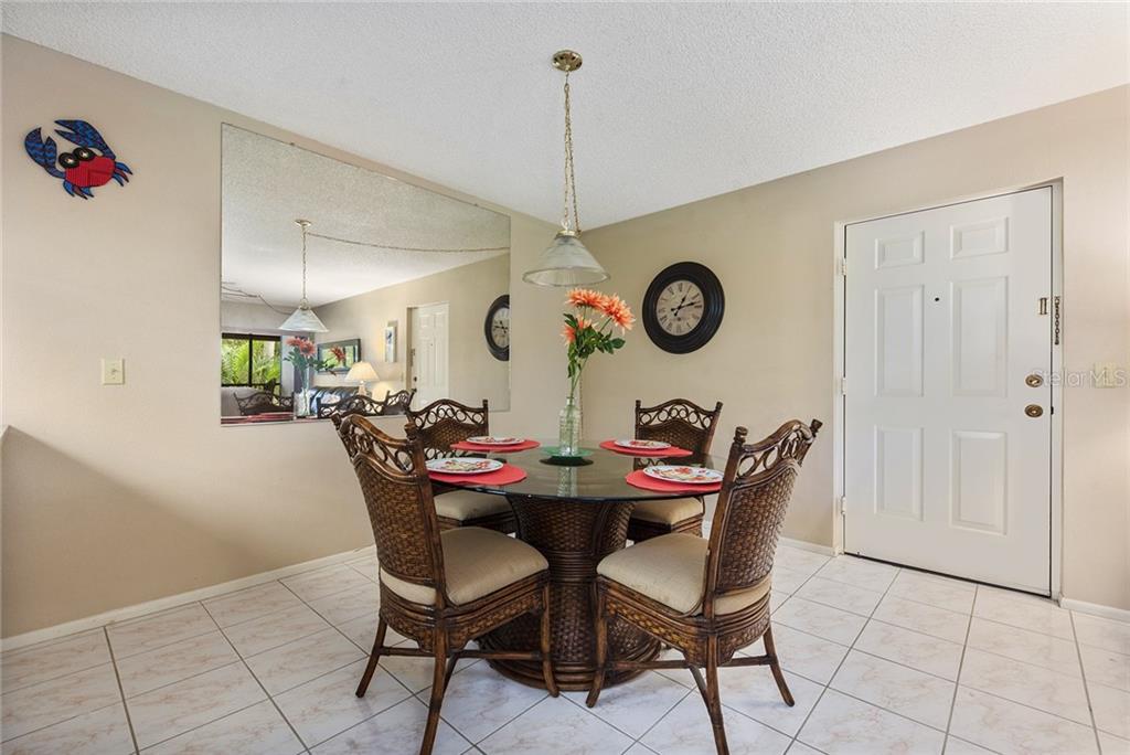 A dining area features a glass-topped table, wicker chairs, a large wall mirror, and tile flooring — 1515 FORREST NELSON BOULEVARD UNIT C202, PORT CHARLOTTE, FL