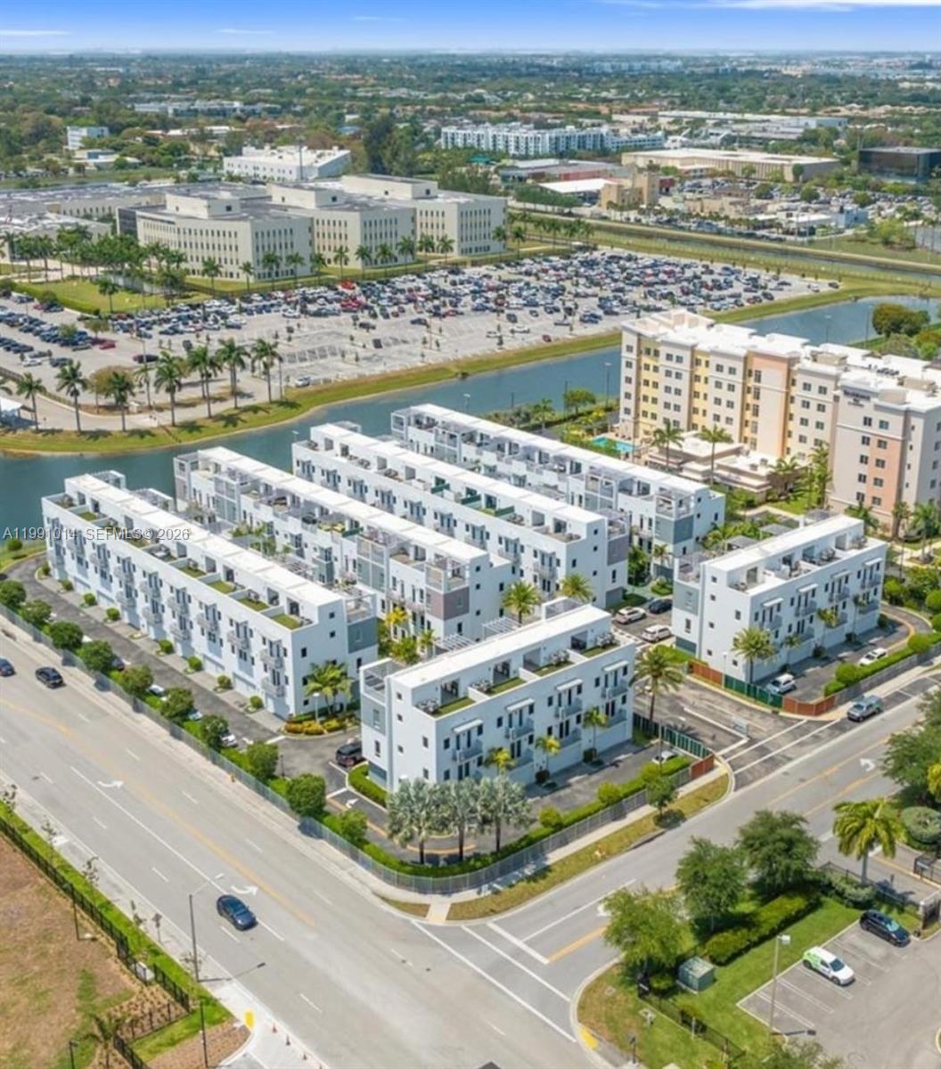 An aerial view of a modern white townhouse complex situated next to a canal — 9133 NW 33rd St, Doral FL 33172, DORAL, FL