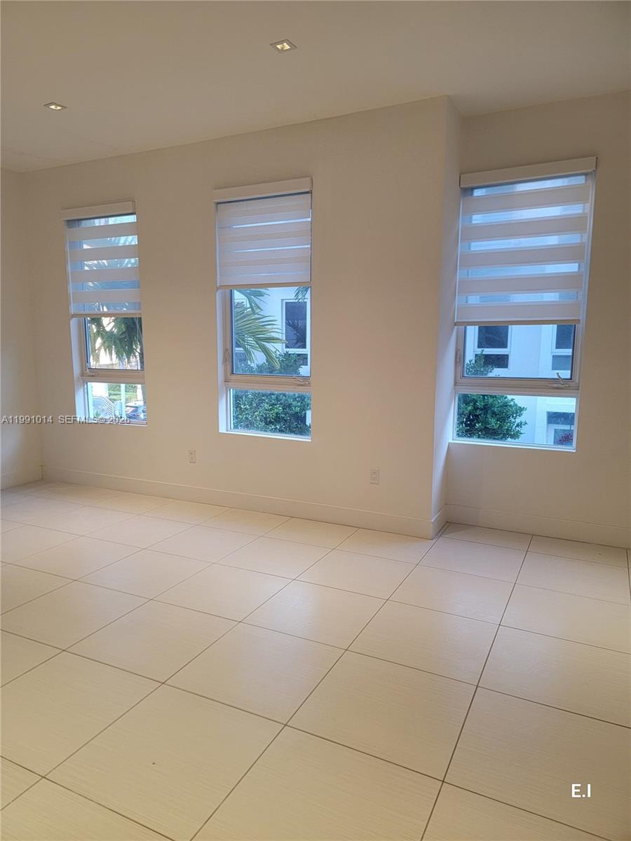 A bright, empty room features large windows with zebra blinds and light-colored tile flooring — 9133 NW 33rd St, Doral FL 33172, DORAL, FL