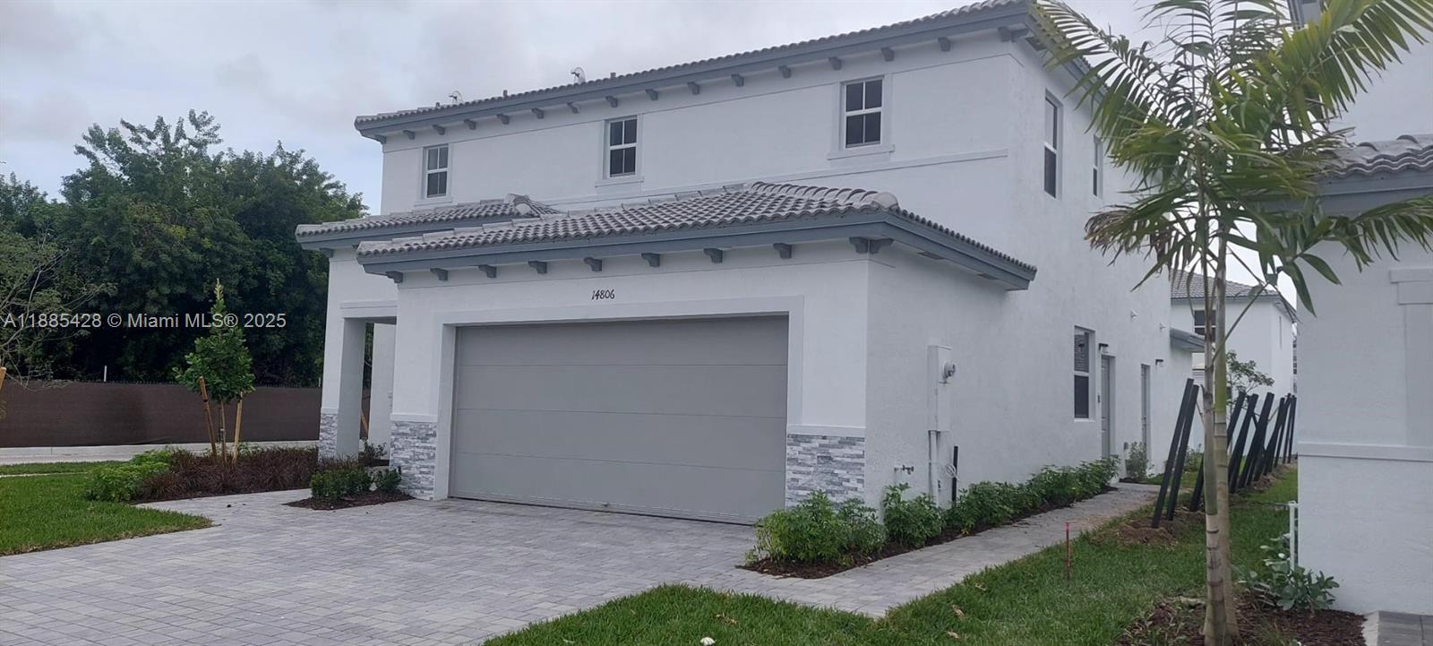 A two-story white house features a gray garage door, stone accents, and a tiled roof — 14806 SW 163rd St, Miami FL 33187, MIAMI, FL