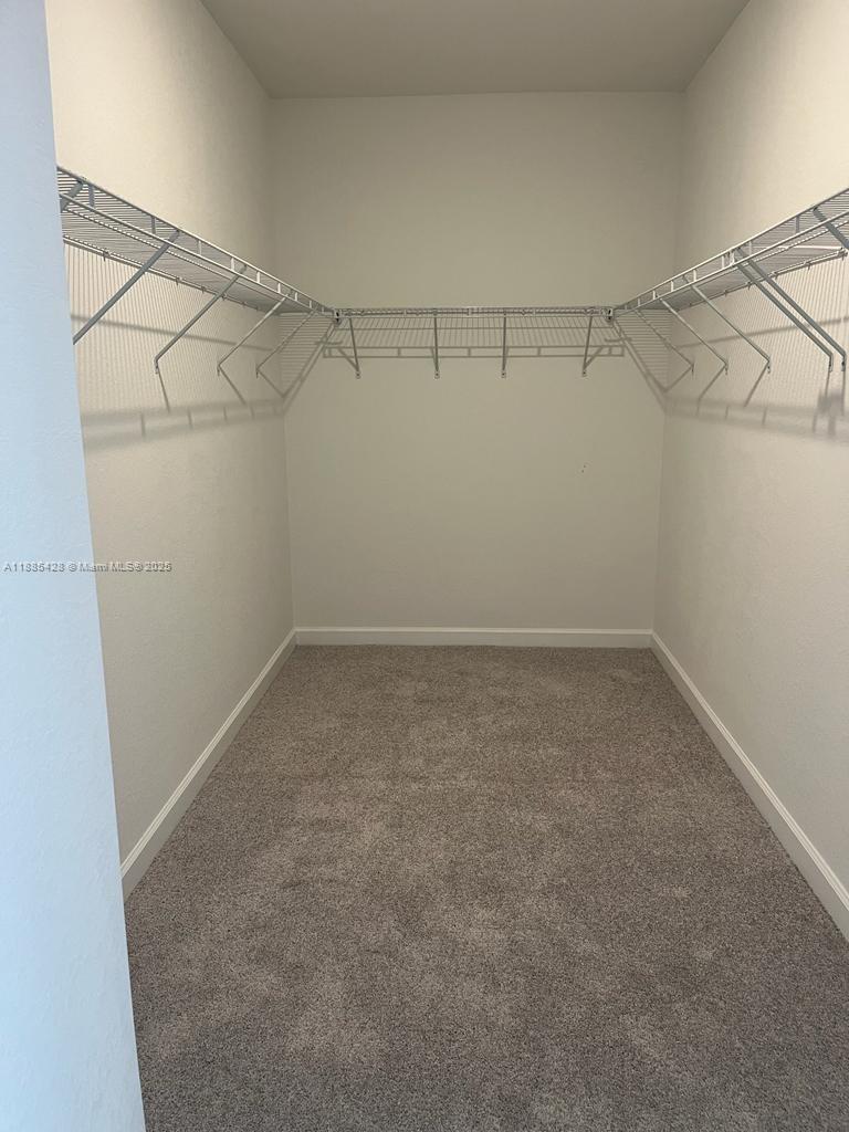 A walk-in closet features white wire shelving and gray carpeting — 14806 SW 163rd St, Miami FL 33187, MIAMI, FL