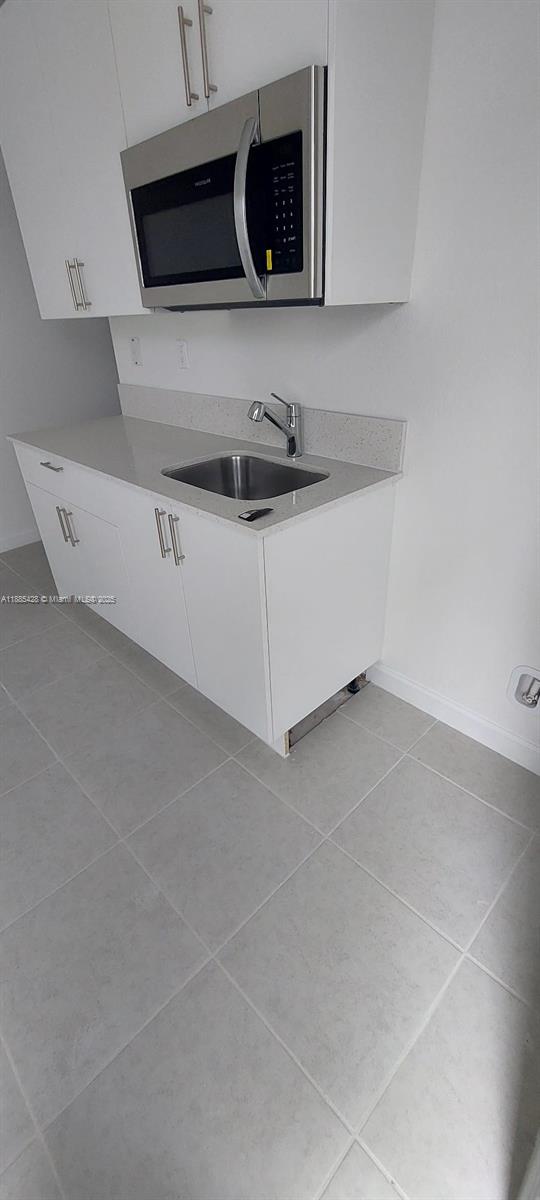 A small kitchen area features white cabinets, a stainless steel microwave, and a single sink — 14806 SW 163rd St, Miami FL 33187, MIAMI, FL