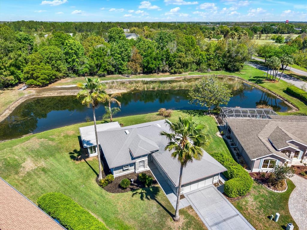 An aerial view of a suburban house with a pool cage next to a pond — 29451 SCHINNECOCK HILLS LANE, SAN ANTONIO, FL