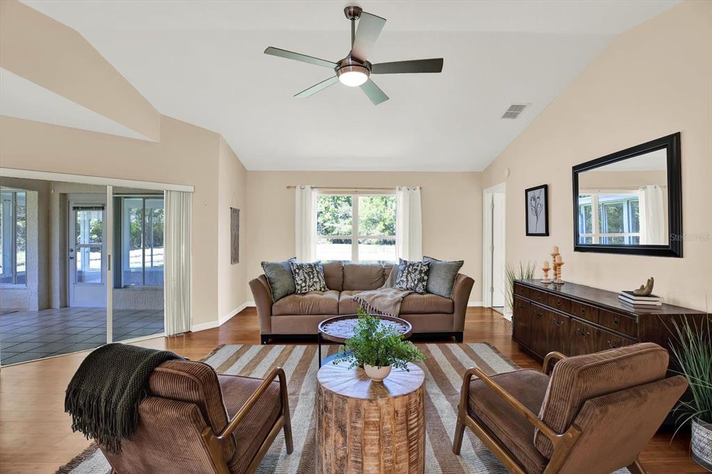 A living room features a brown sofa, two armchairs, a wooden coffee table, and hardwood floors — 29451 SCHINNECOCK HILLS LANE, SAN ANTONIO, FL