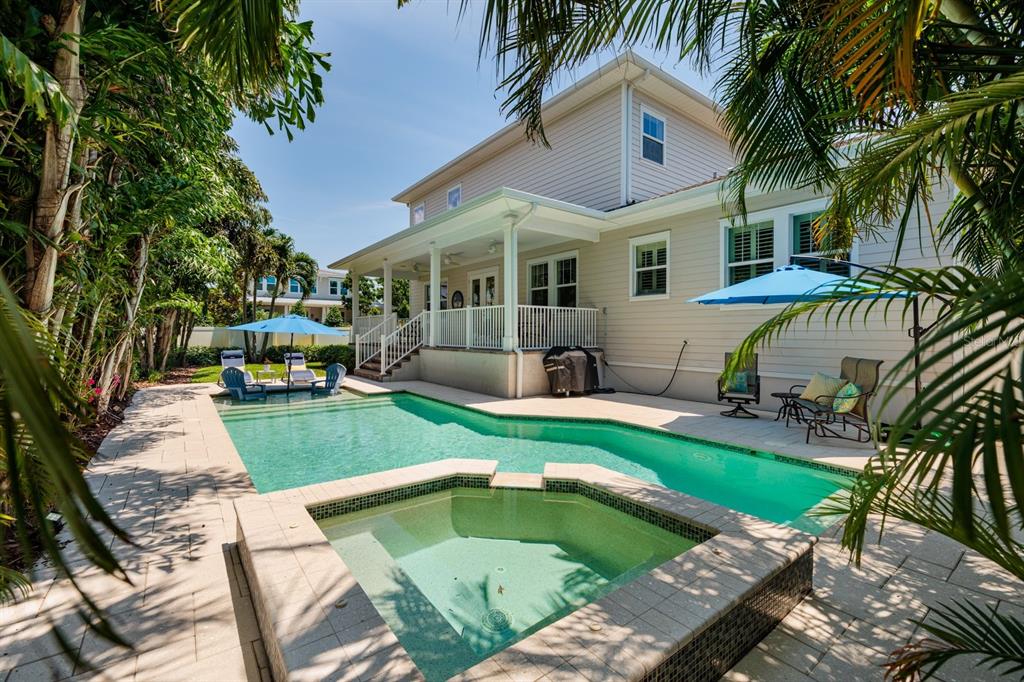 A backyard features a swimming pool, a raised spa, a covered patio, and palm trees — 852 CORDOVA BOULEVARD NE, ST PETERSBURG, FL