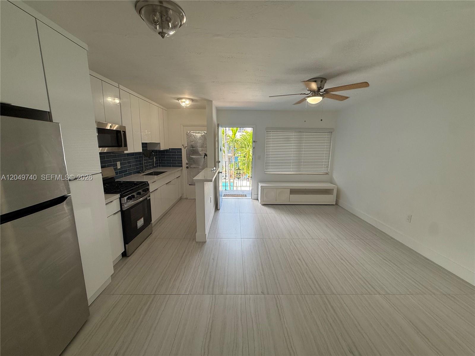 A kitchen with white cabinets and stainless steel appliances opens into a living area — 7441 SW 59th Pl # 28, South Miami FL 33143, SOUTH MIAMI, FL