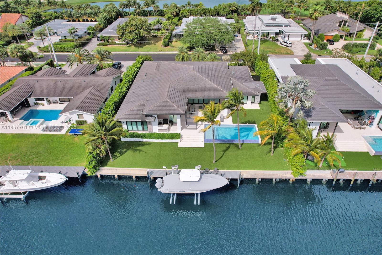 An aerial view shows a waterfront house with a pool, lawn, and two docked boats — 1651 Diplomat Pkwy, Hallandale Beach FL 33009, HALLANDALE BEACH, FL