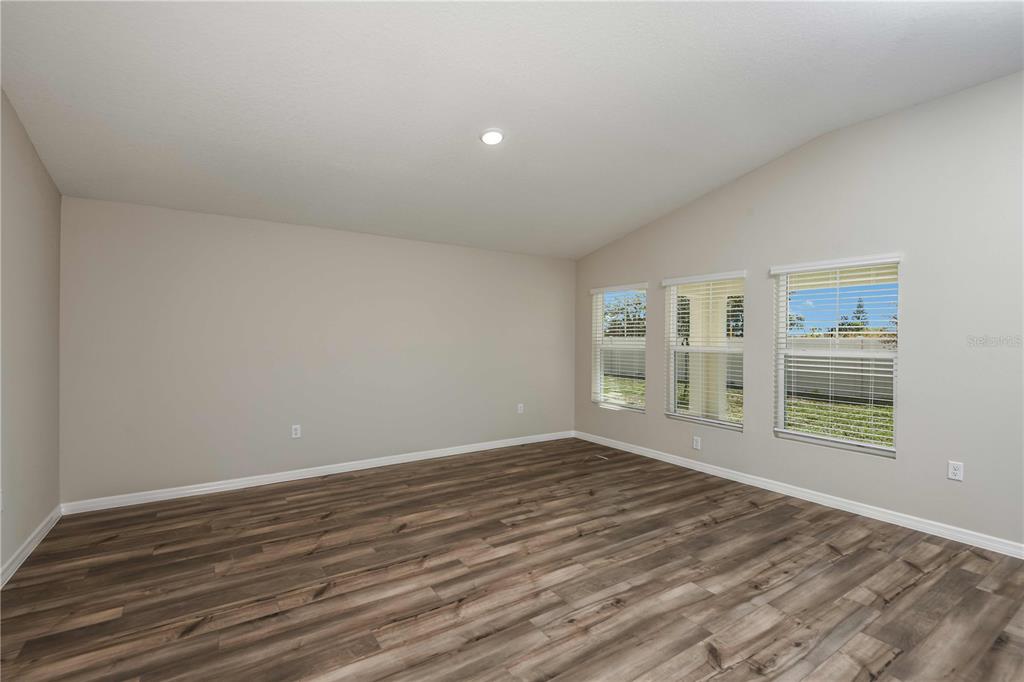 An empty room with light-colored walls, wood-look flooring, and three windows with blinds — 1362 PALMEROY ROAD, HAINES CITY, FL