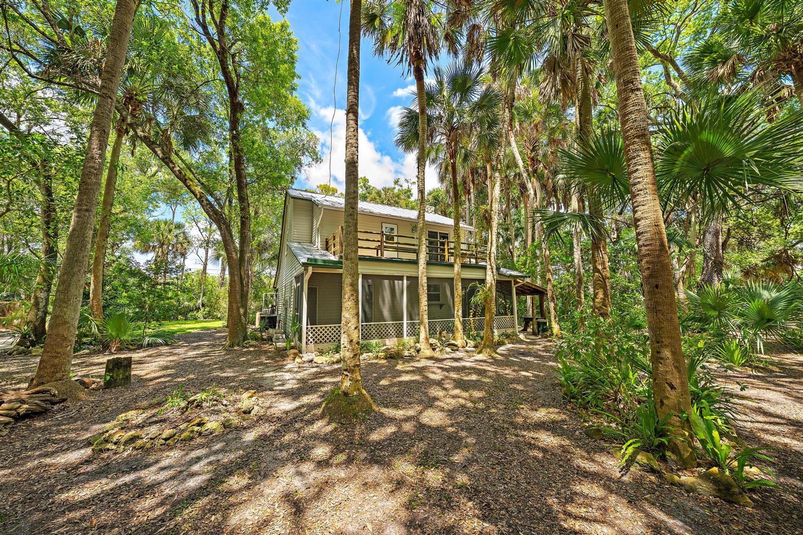 A two-story house with a screened porch and balcony sits in a wooded, shaded yard — 15740 N 99th St Street N, FL 33412, FL