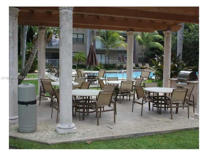 A covered outdoor patio area features multiple dining tables and chairs near a swimming pool — 9301 SW 92nd Ave # 207C, Miami FL 33176, MIAMI, FL