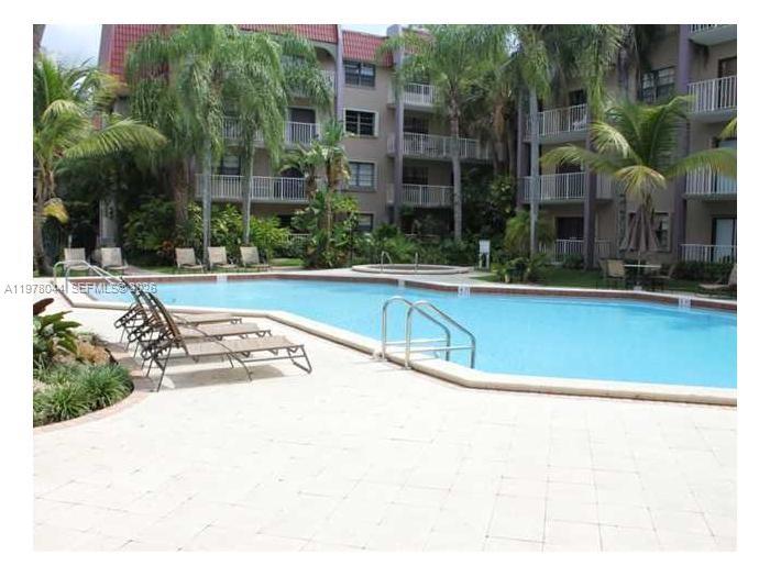 A swimming pool with lounge chairs sits in front of a multi-story apartment building — 9301 SW 92nd Ave # 207C, Miami FL 33176, MIAMI, FL