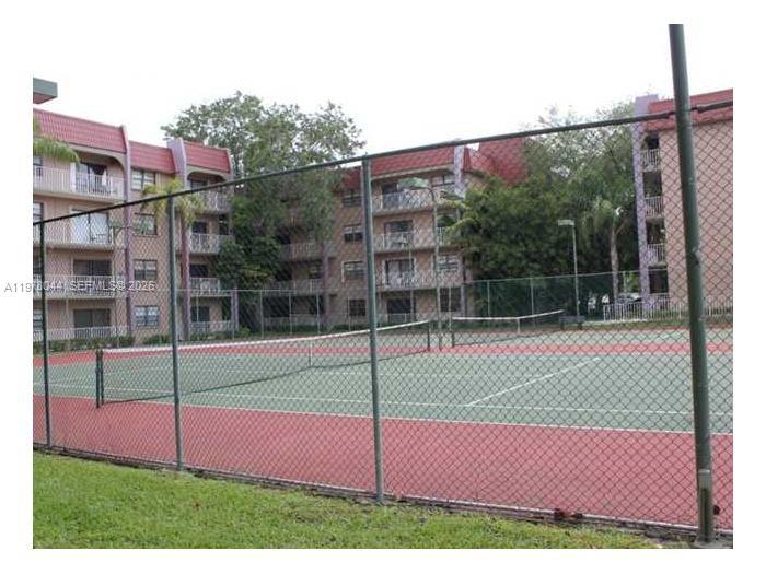 A tennis court with a chain-link fence sits in front of a multi-story apartment building — 9301 SW 92nd Ave # 207C, Miami FL 33176, MIAMI, FL