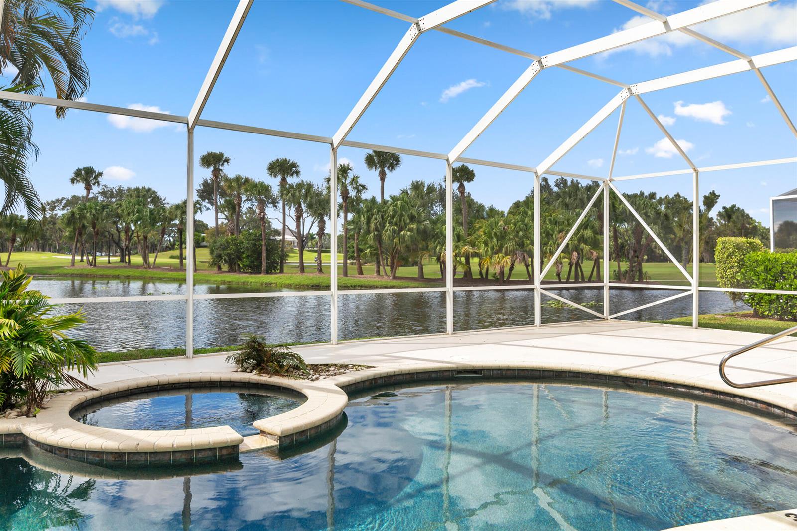 A screened-in pool and hot tub overlook a lake and golf course with palm trees — 9741 Spray Drive, West Palm Beach FL 33411, WEST PALM BEACH, FL