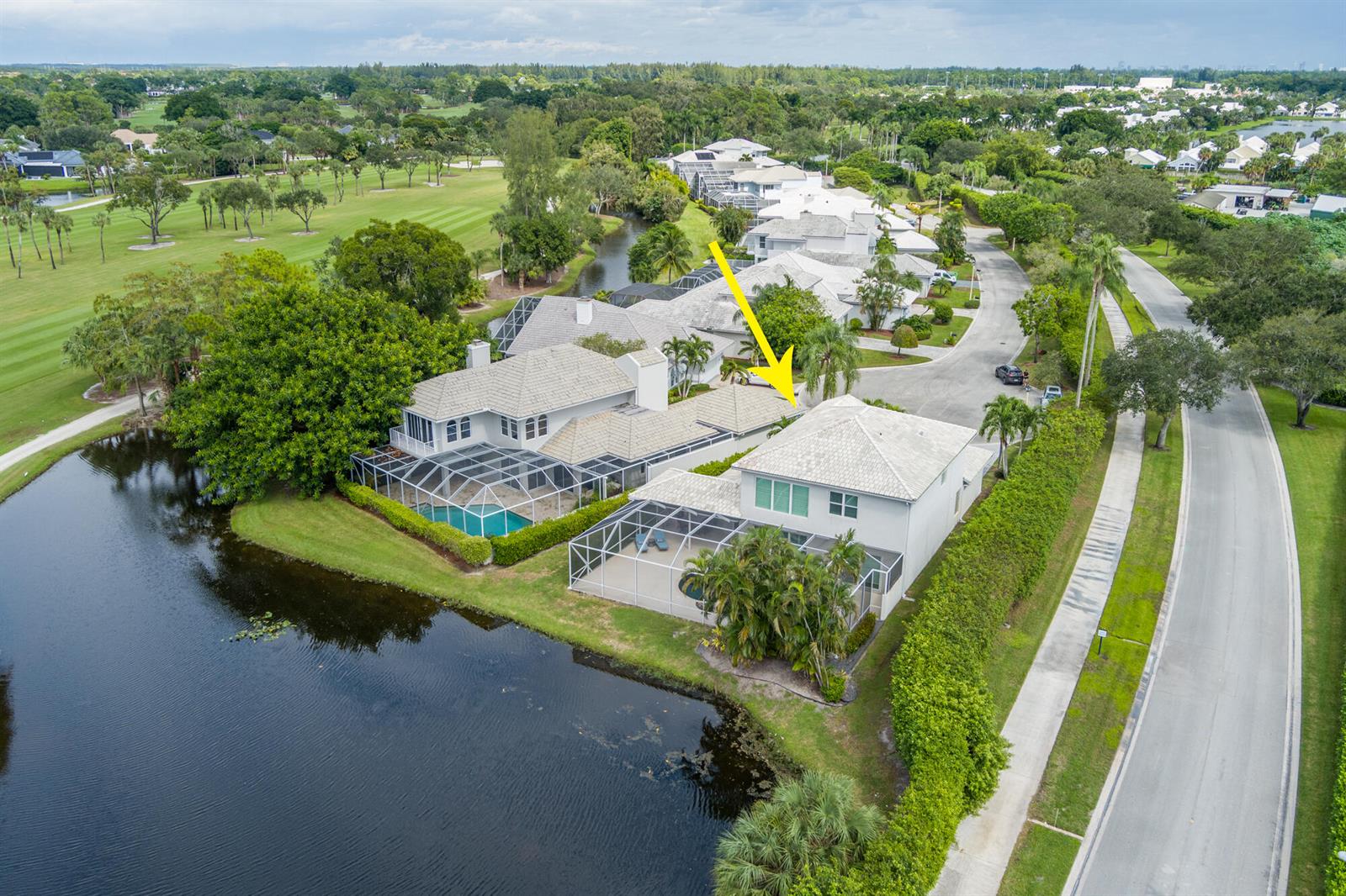An aerial view shows two adjacent houses with screened-in pools overlooking a pond and golf course — 9741 Spray Drive, West Palm Beach FL 33411, WEST PALM BEACH, FL