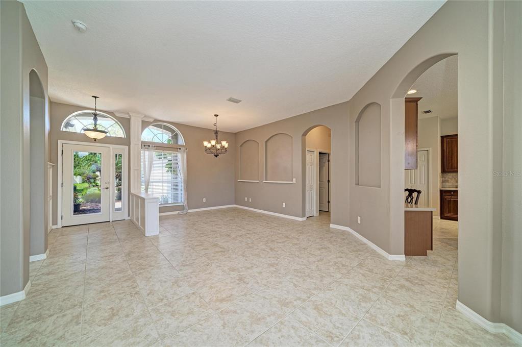 A spacious living area features beige tile flooring, arched wall niches, and a front entryway — 12626 30TH STREET CIRCLE E, PARRISH, FL