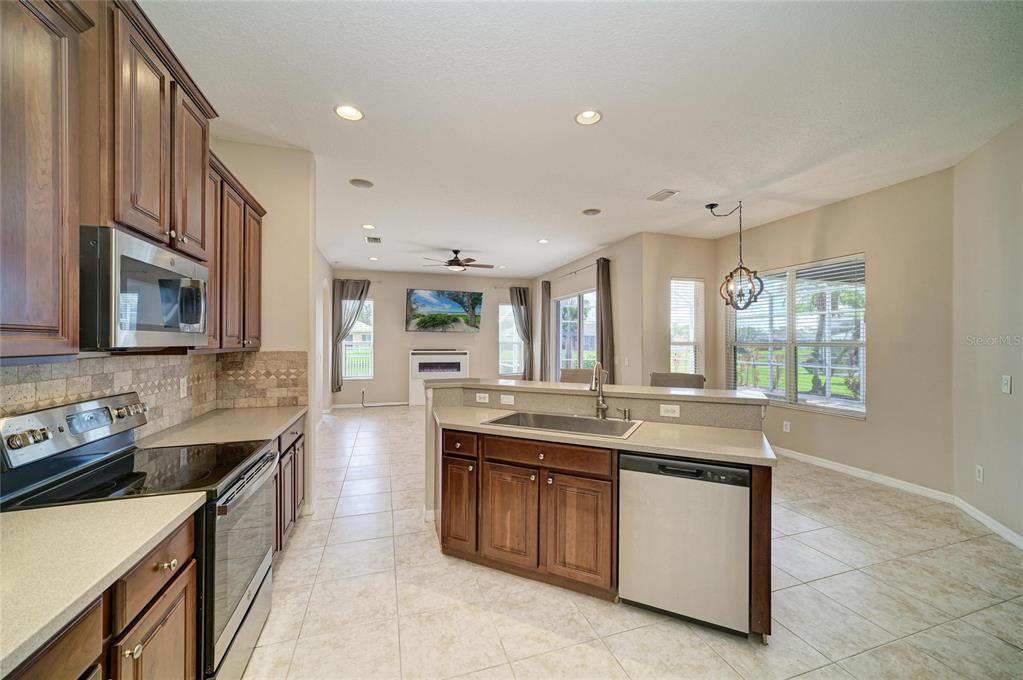 A kitchen with dark wood cabinets, stainless steel appliances, and a central island with sink — 12626 30TH STREET CIRCLE E, PARRISH, FL