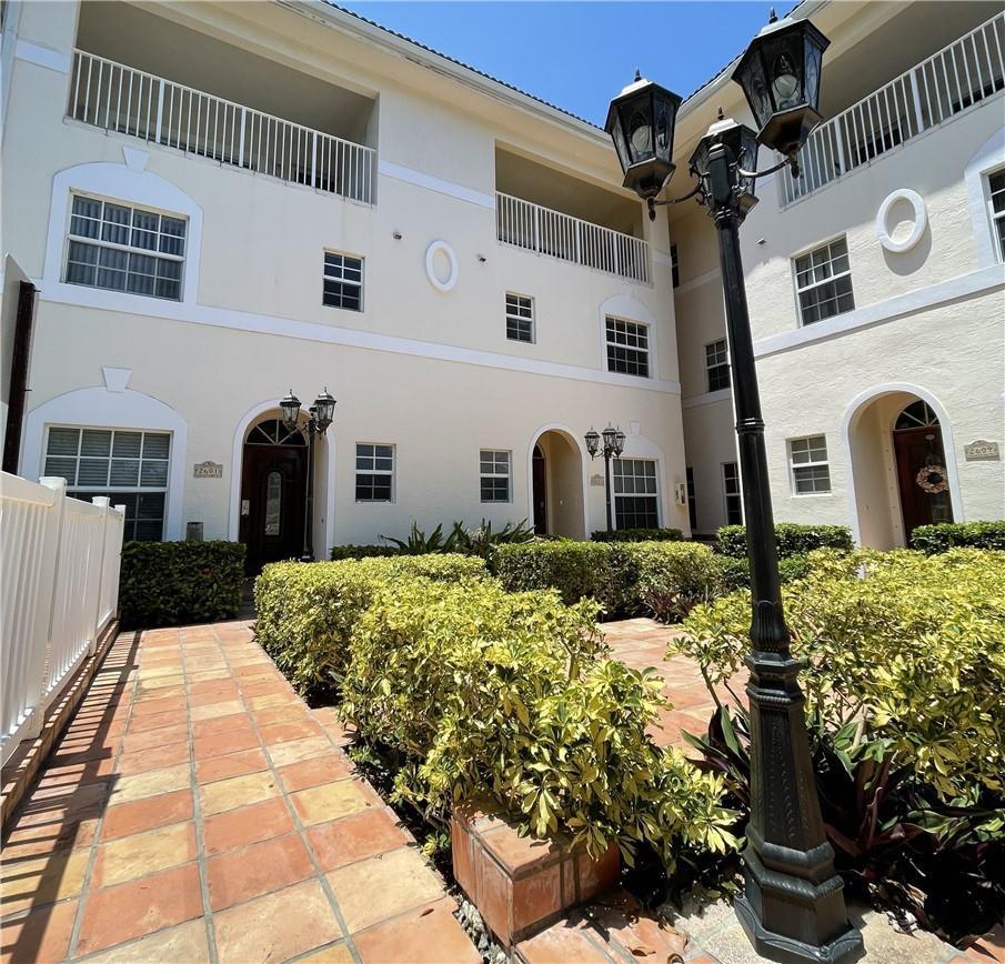 An exterior view of a multi-story apartment building with a tiled courtyard and landscaping — 2605 Bay Drive, Pompano Beach FL 33062, POMPANO BEACH, FL