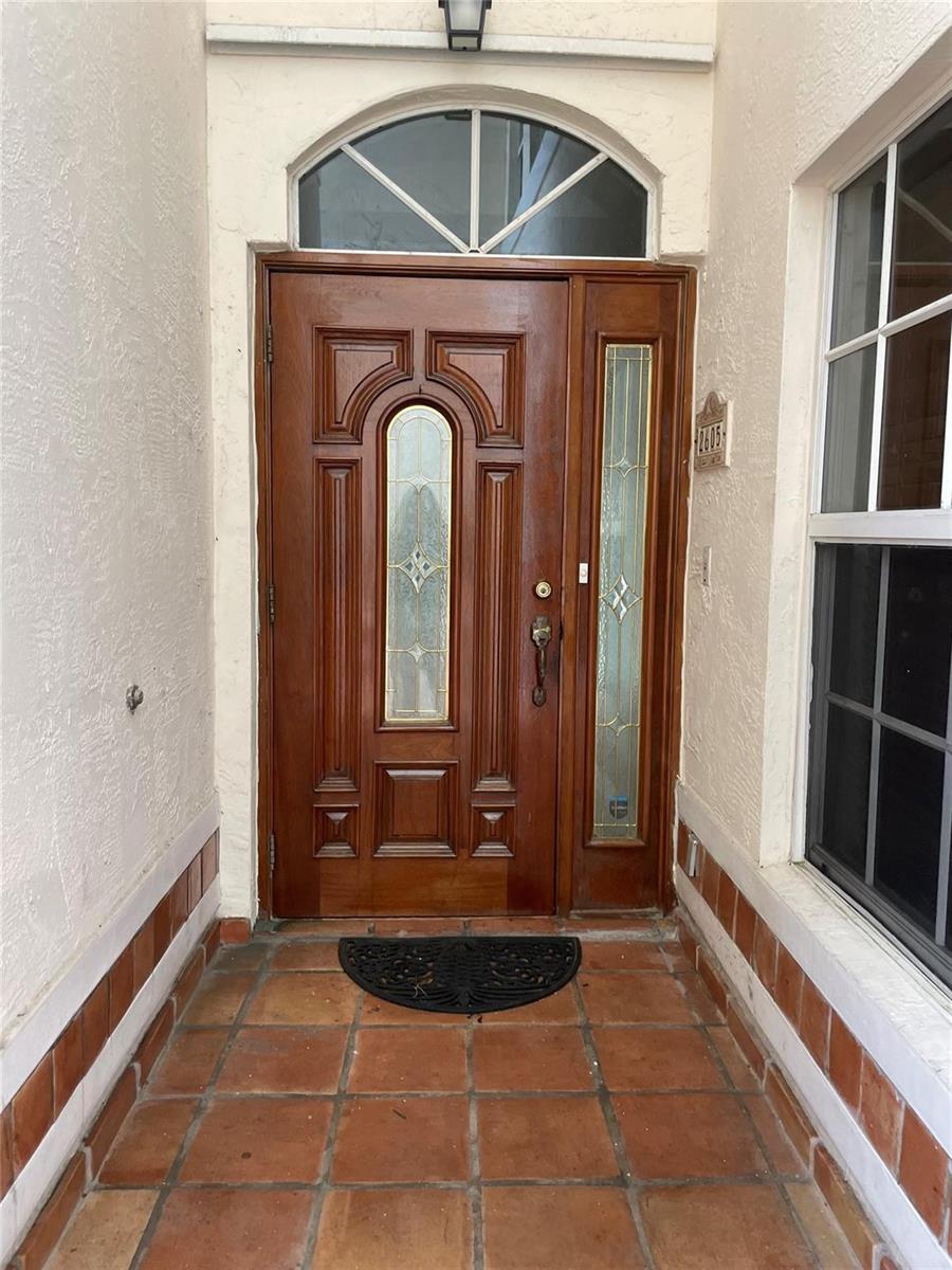 A wooden front door with a glass insert and sidelight sits on a tiled porch — 2605 Bay Drive, Pompano Beach FL 33062, POMPANO BEACH, FL