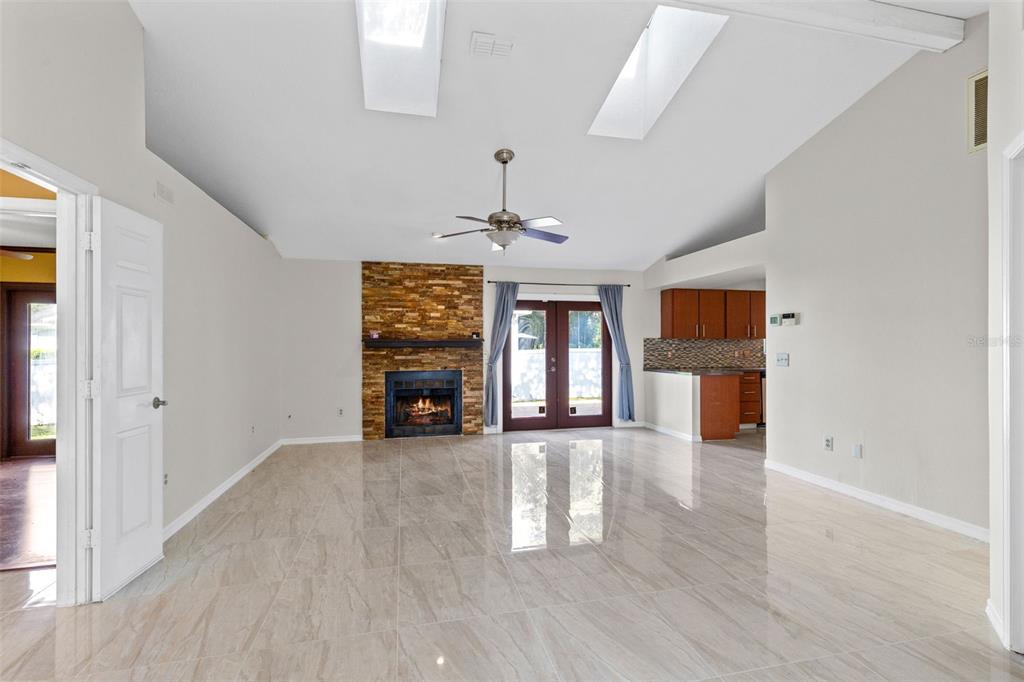 A living room with tile floors, a stone fireplace, a ceiling fan, and skylights — 2780 PASEO AVENUE, ORLANDO, FL