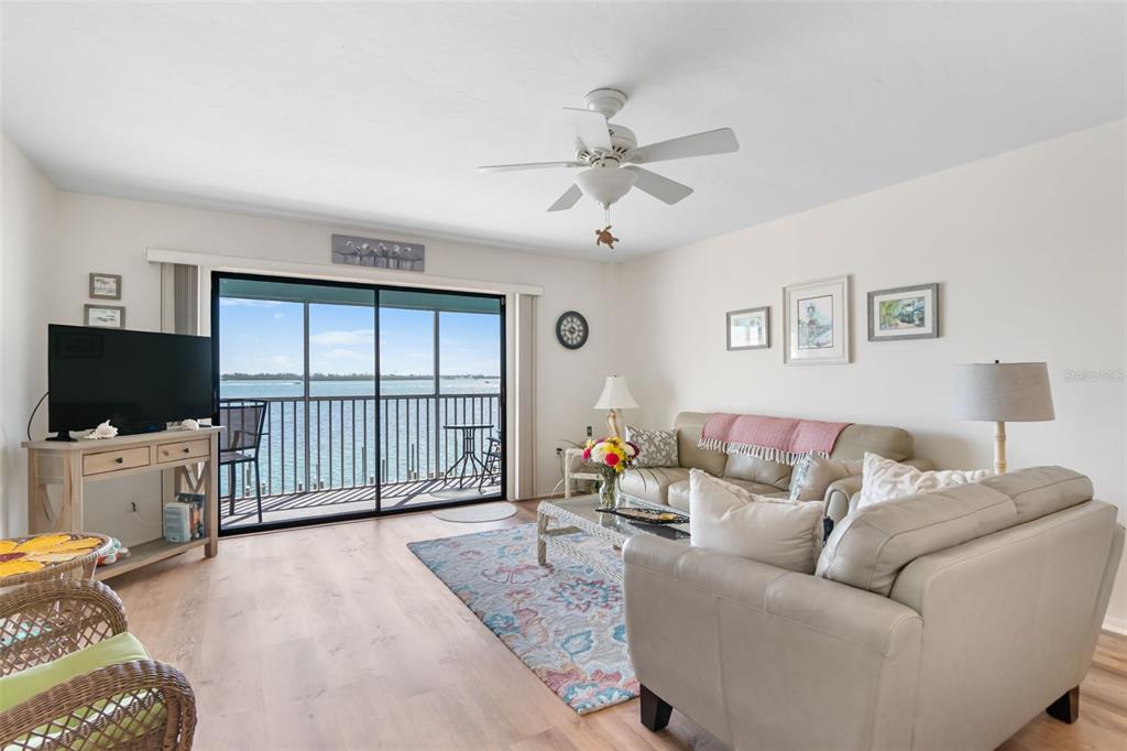 A living room features a beige sofa, area rug, ceiling fan, and sliding glass balcony doors — 901 GULF DRIVE S UNIT 14, BRADENTON BEACH, FL