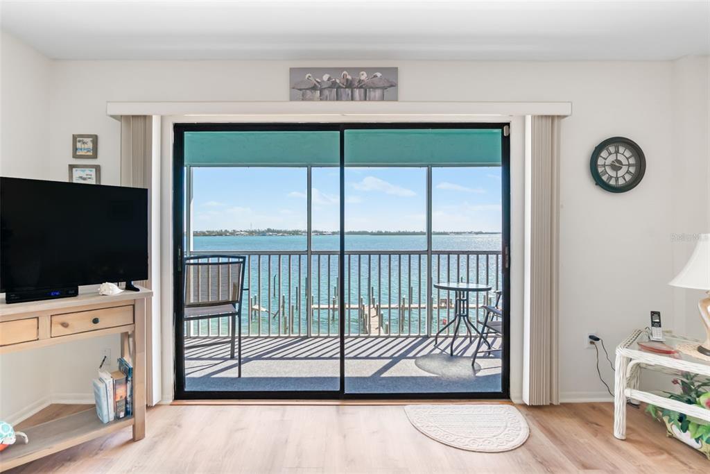 A living room features a sliding glass door opening to a balcony overlooking the water — 901 GULF DRIVE S UNIT 14, BRADENTON BEACH, FL
