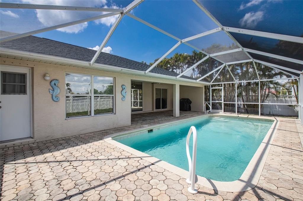 A screened-in patio features a swimming pool with a white handrail and paver flooring — 5333 SW 16TH PLACE, CAPE CORAL, FL
