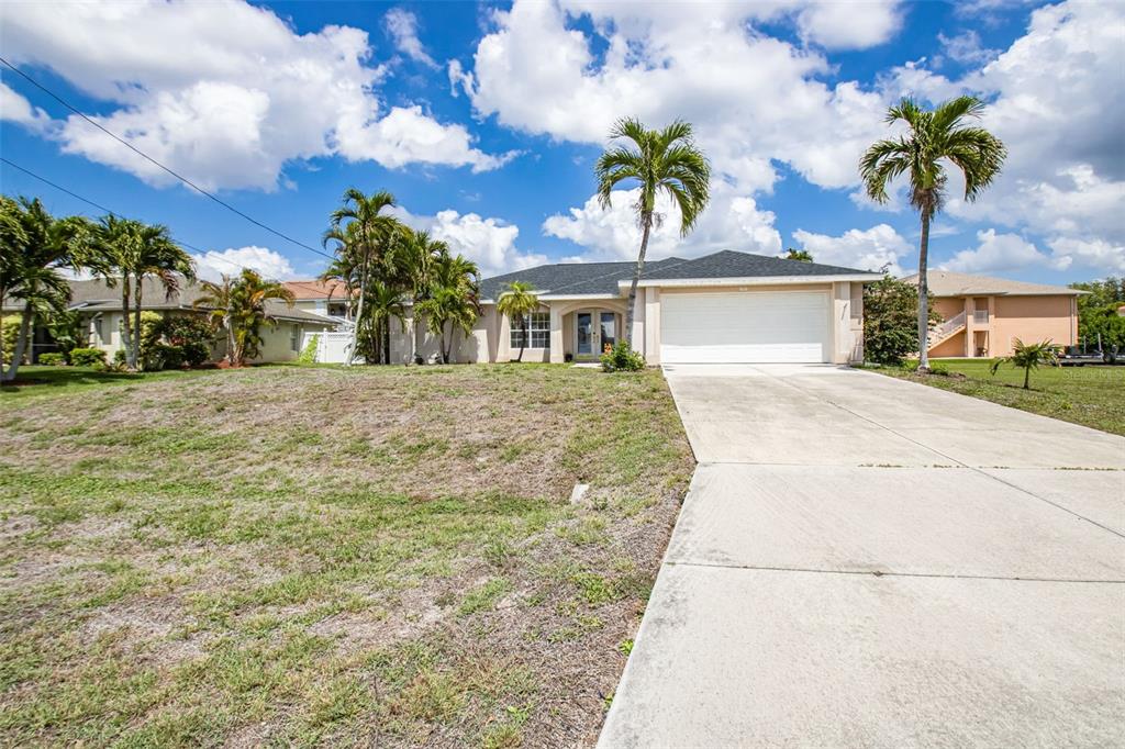 A single-story house with a white garage and palm trees sits under a cloudy sky — 5333 SW 16TH PLACE, CAPE CORAL, FL