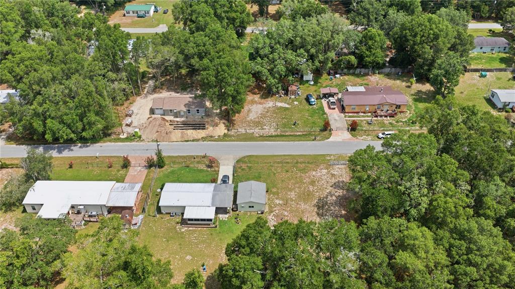 An aerial view shows several houses with driveways and yards surrounded by dense green trees — 11140 SW 109TH PLACE, DUNNELLON, FL