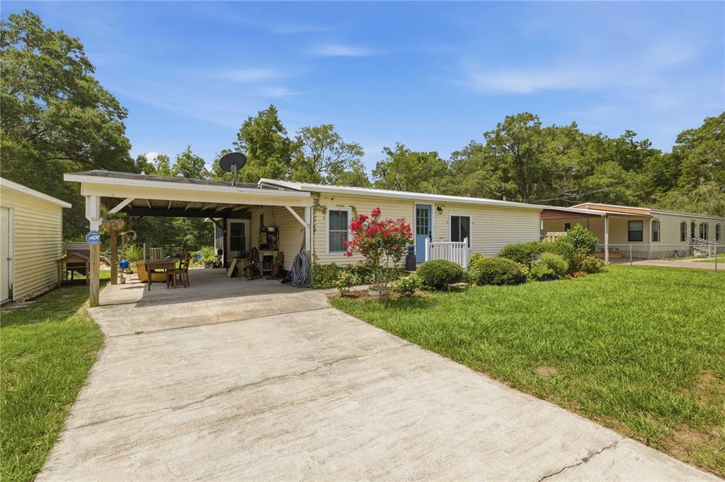 A single-story house with light siding, a concrete driveway, and an attached carport — 11140 SW 109TH PLACE, DUNNELLON, FL