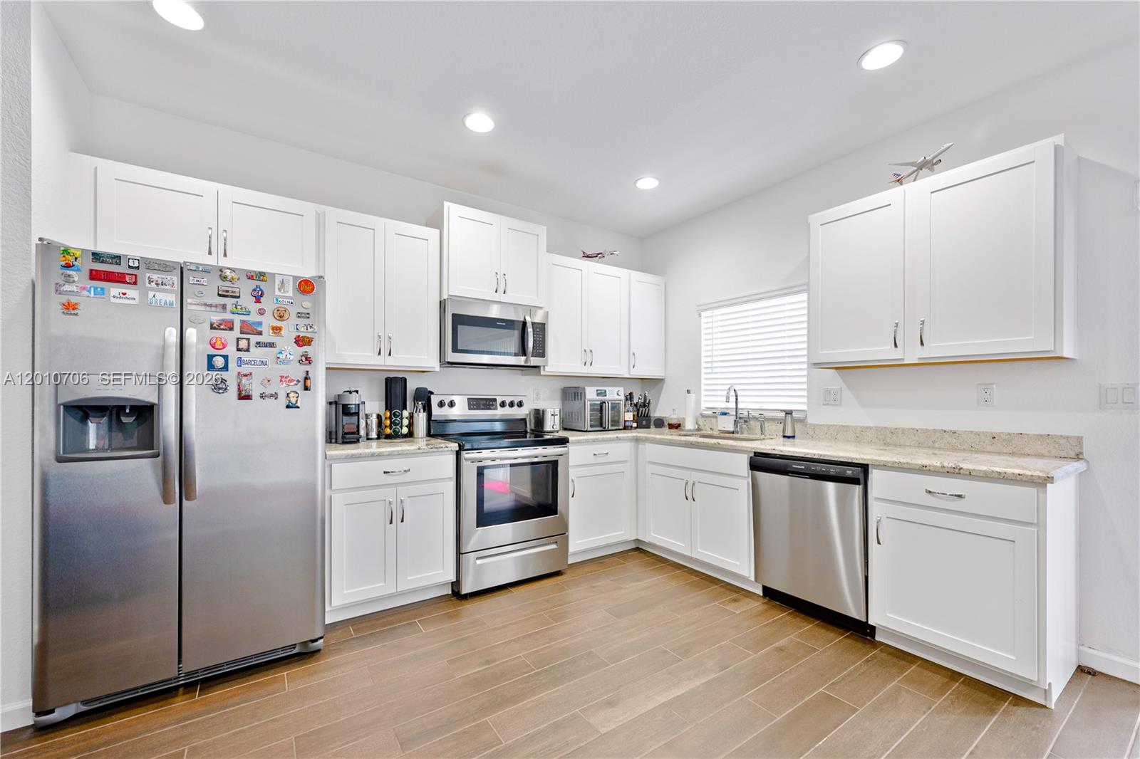 A kitchen features white cabinets, stainless steel appliances, and light-colored granite countertops — 1106 NW 40th Ter, Lauderhill FL 33313, LAUDERHILL, FL