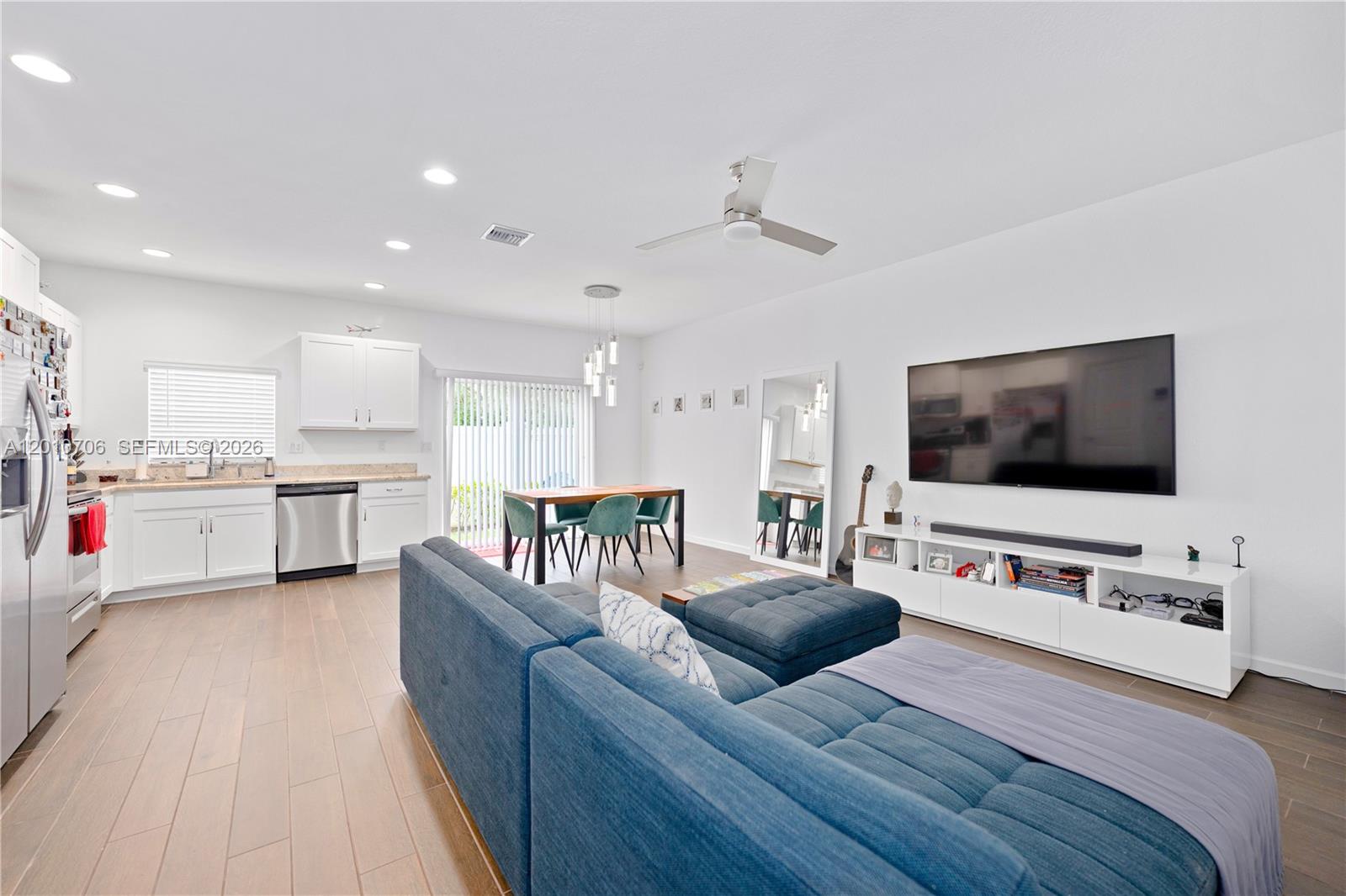 An open-concept living area features a kitchen, dining space, and a blue sectional sofa — 1106 NW 40th Ter, Lauderhill FL 33313, LAUDERHILL, FL