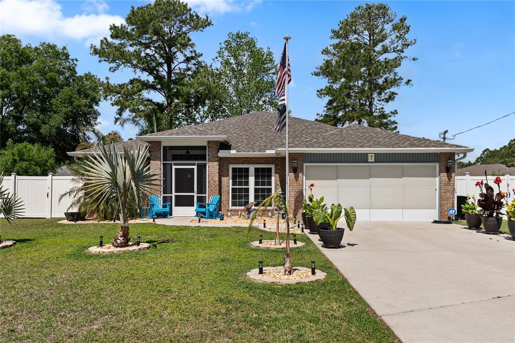 A single-story brick house features a screened front porch, a two-car garage, and a flagpole — 7 RANBAY PLACE, PALM COAST, FL