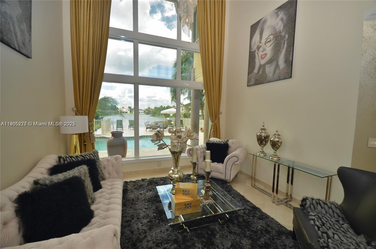 A living room features tall windows, gold curtains, a tufted sofa, and a pool view — 16232 NW 79th Ave, Miami Lakes FL 33016, MIAMI LAKES, FL
