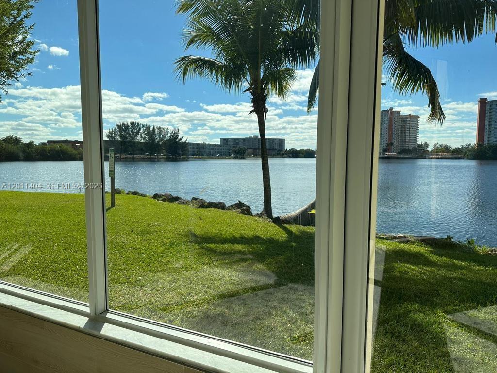 A view of a lake and palm trees seen through a large window — 1302 NE 191st St # A114, Miami FL 33179, MIAMI, FL