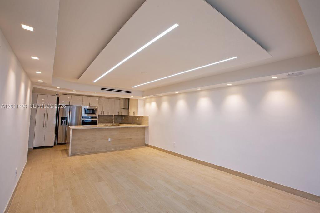 A modern kitchen features light wood cabinetry, a breakfast bar, and recessed ceiling lighting — 1302 NE 191st St # A114, Miami FL 33179, MIAMI, FL