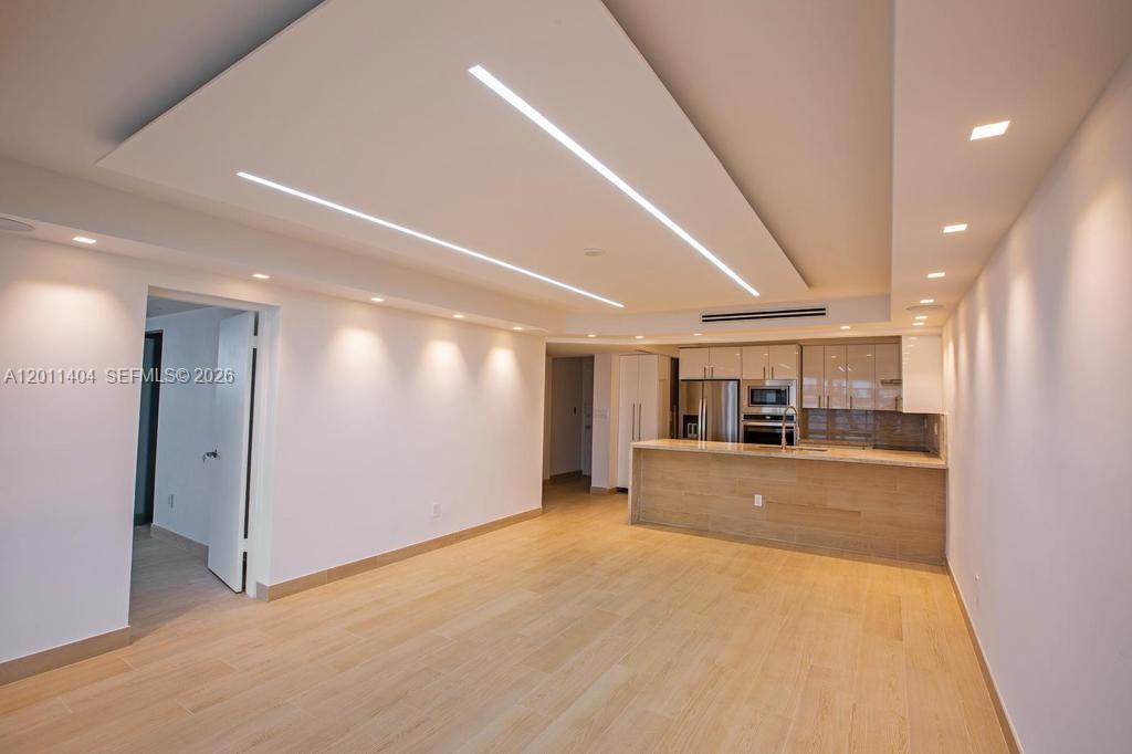A modern, open-concept living area features light wood flooring and a recessed ceiling light fixture — 1302 NE 191st St # A114, Miami FL 33179, MIAMI, FL