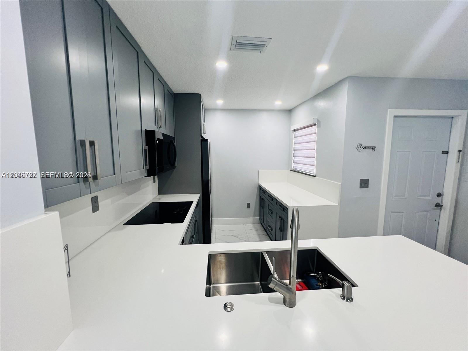 A modern kitchen features gray cabinets, white countertops, stainless steel appliances, and a double sink — 12526 NW 11th Trl # 207, Miami FL 33182, MIAMI, FL