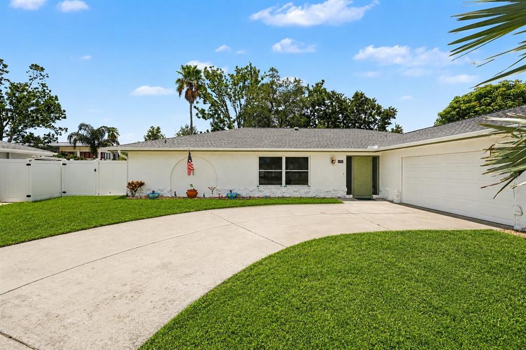 A single-story white house with a concrete driveway, a two-car garage, and a green door — 1501 NEW BEDFORD DRIVE, SUN CITY CENTER, FL