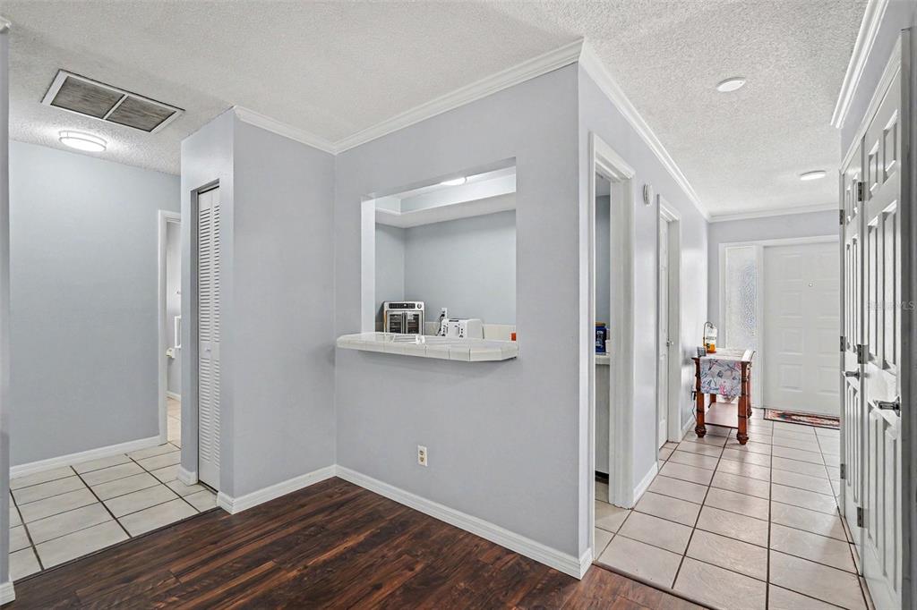A view of an interior hallway with tile and wood flooring and a kitchen pass-through — 1501 NEW BEDFORD DRIVE, SUN CITY CENTER, FL