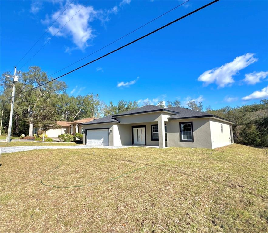 A single-story house with a beige exterior, dark roof, and a two-car garage — 8191 N PICKINZ WAY, CITRUS SPRINGS, FL