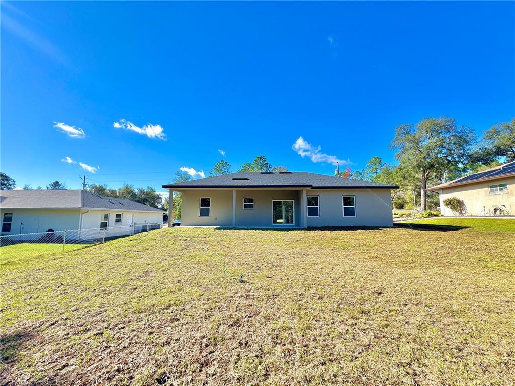 The exterior rear view of a single-story house with a lawn and neighboring homes — 8191 N PICKINZ WAY, CITRUS SPRINGS, FL