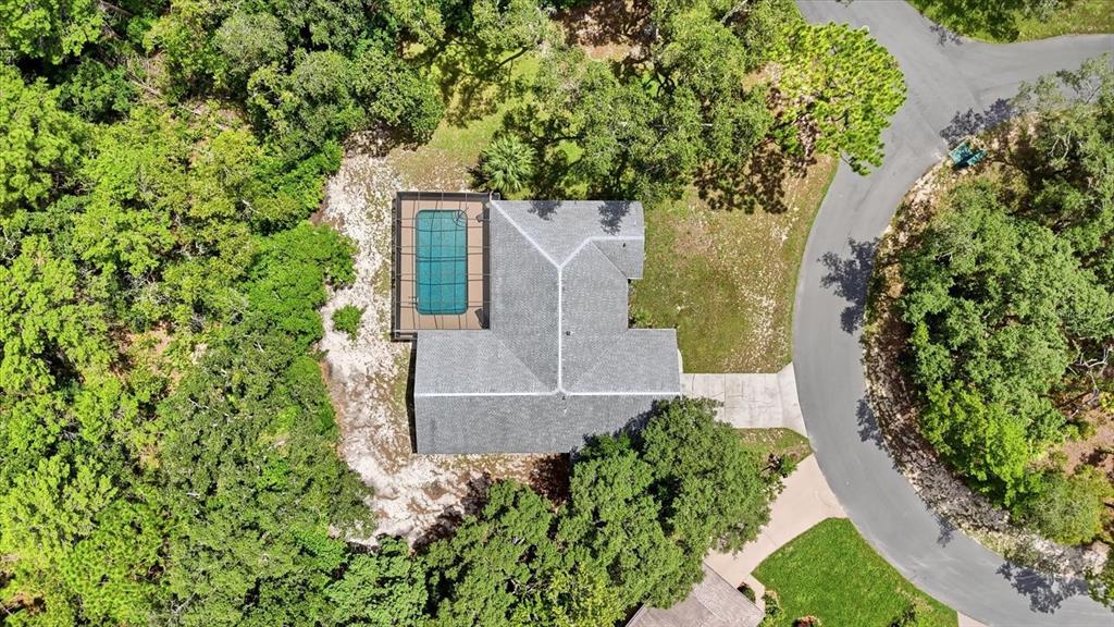 An aerial view shows a house with a screened-in pool surrounded by dense trees — 12 ASTERS COURT, HOMOSASSA, FL
