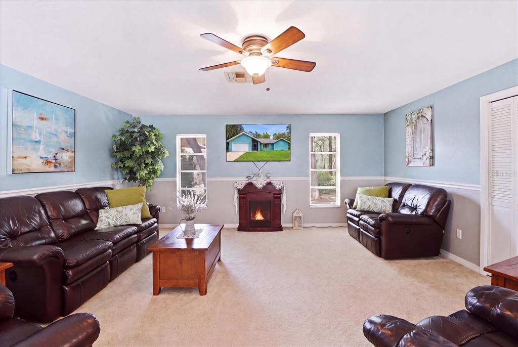 A living room features brown leather sofas, a fireplace, and a television on the wall — 12 ASTERS COURT, HOMOSASSA, FL